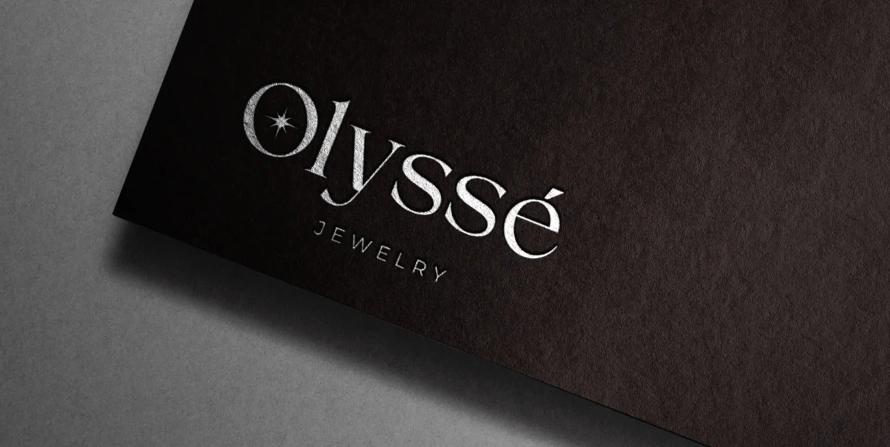 Olyssé Jewelry için tasarlanan logo, markanın lüks ve zarif çizgisini yansıtan modern bir imza niteliğinde. Siyah zemin üzerindeki parlak gümüş detaylar, premium marka kimliğini güçlendirirken, özgün tipografi Olyssé’nin zamansız ve ulaşılabilir lüks anlayışını ön plana çıkarıyor.