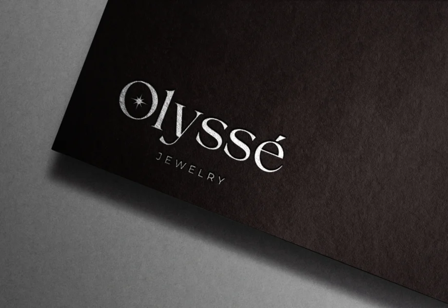 Olyssé Jewelry için tasarlanan logo, markanın lüks ve zarif çizgisini yansıtan modern bir imza niteliğinde. Siyah zemin üzerindeki parlak gümüş detaylar, premium marka kimliğini güçlendirirken, özgün tipografi Olyssé’nin zamansız ve ulaşılabilir lüks anlayışını ön plana çıkarıyor.